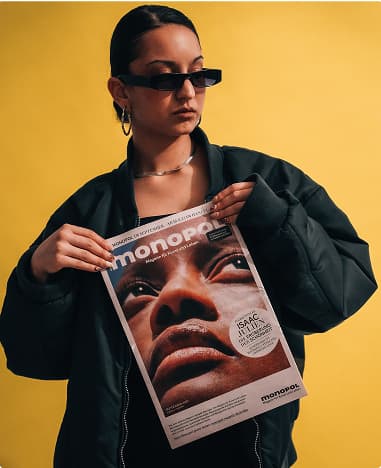 Woman in black jacket and sunglasses holding a magazine