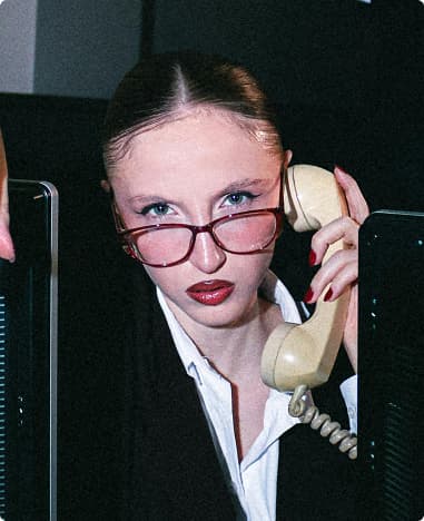 Woman with red glasses talking on a vintage telephone