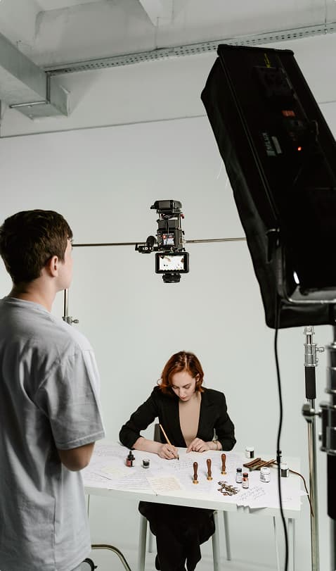 Behind the scenes of a video shoot with a woman doing calligraphy
